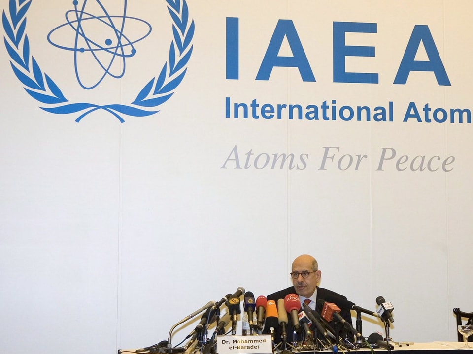 Mohammed el-Baradei sitz vor einem Logo der Internationalen Atomenergie-Organisation