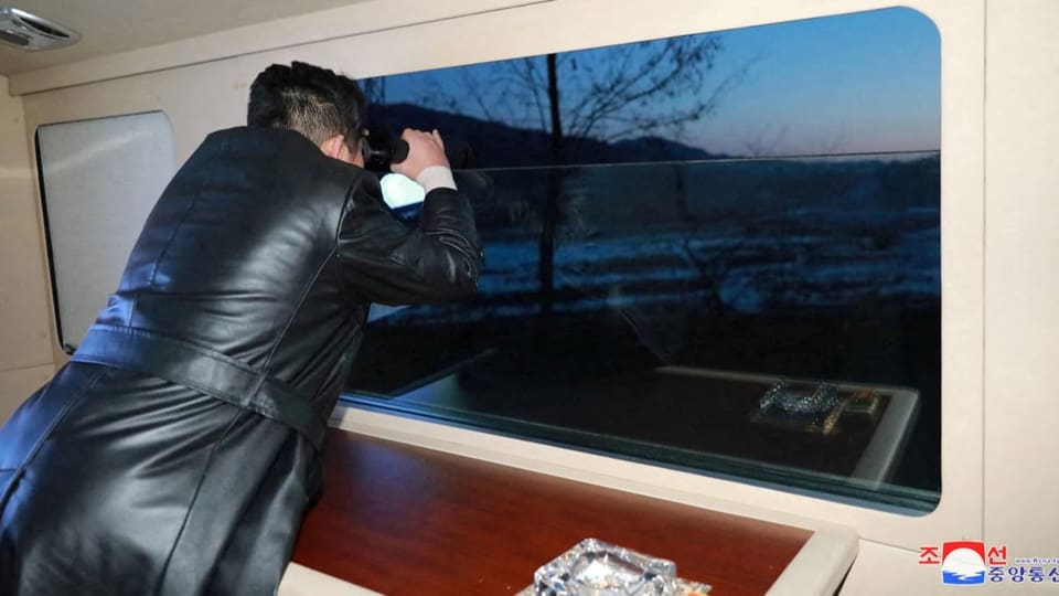 Kim Jong Un beobachtet mit einem Fernglas den Raketenstart aus einem Fenster.