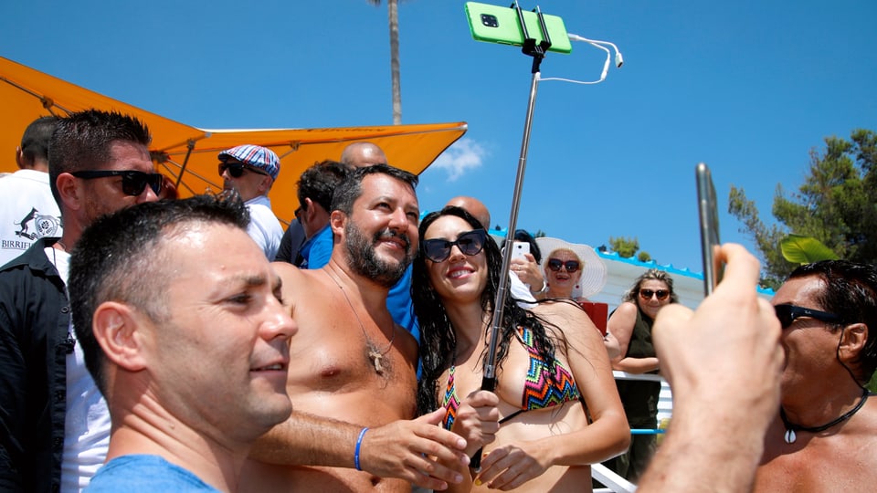 Matteo Salvini posiert mit Anhängern am Strand für ein Selfie.