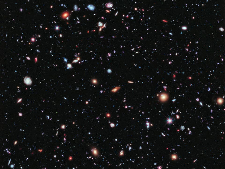 Ein buntes Bild mit Sternen und Galaxien vor schwarzem Hintergrund.