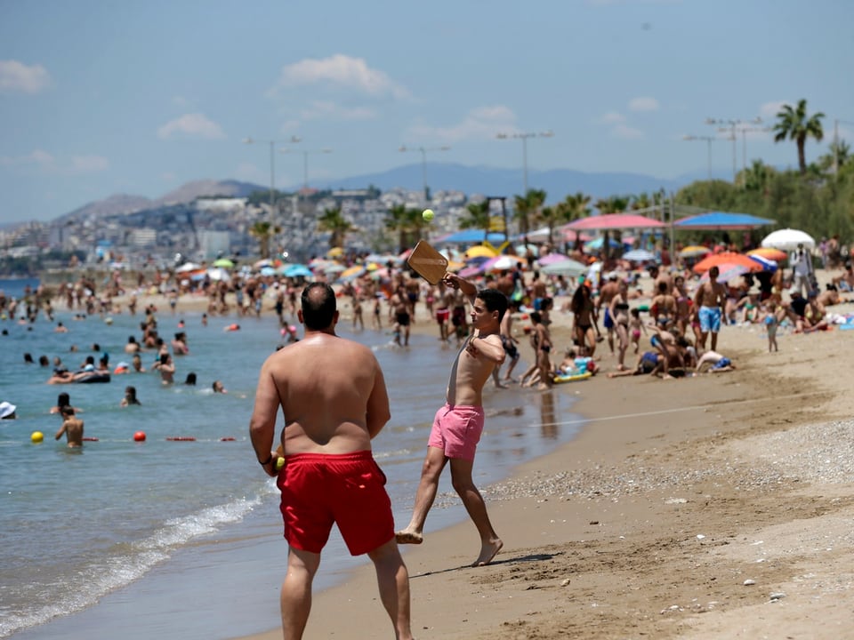 Menschen vergnügen sich am Strand im Süden von Athen. 