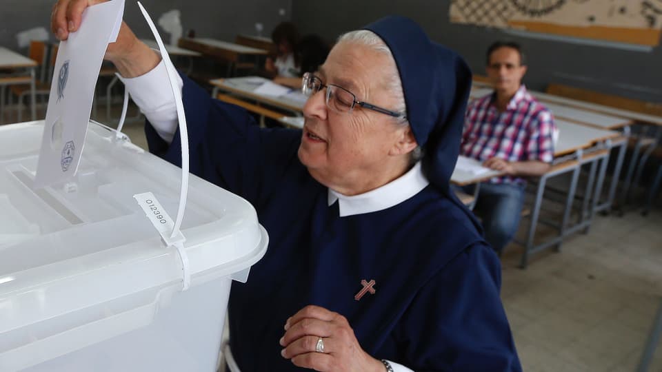 Eine Nonne wirft ihren Stimmzettel in die Urne.