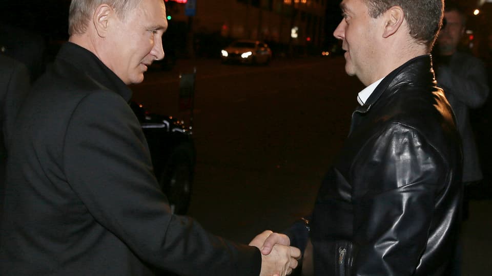 Vladimir Putin schüttelt Ministerpräsident Medwedew diee Hand.