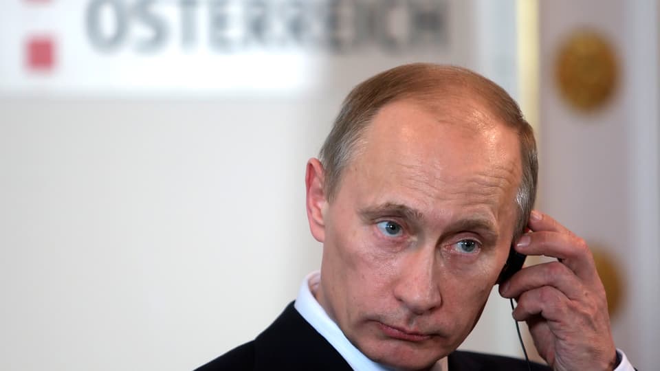 Wladimir Putin an einem Kopfhörer.