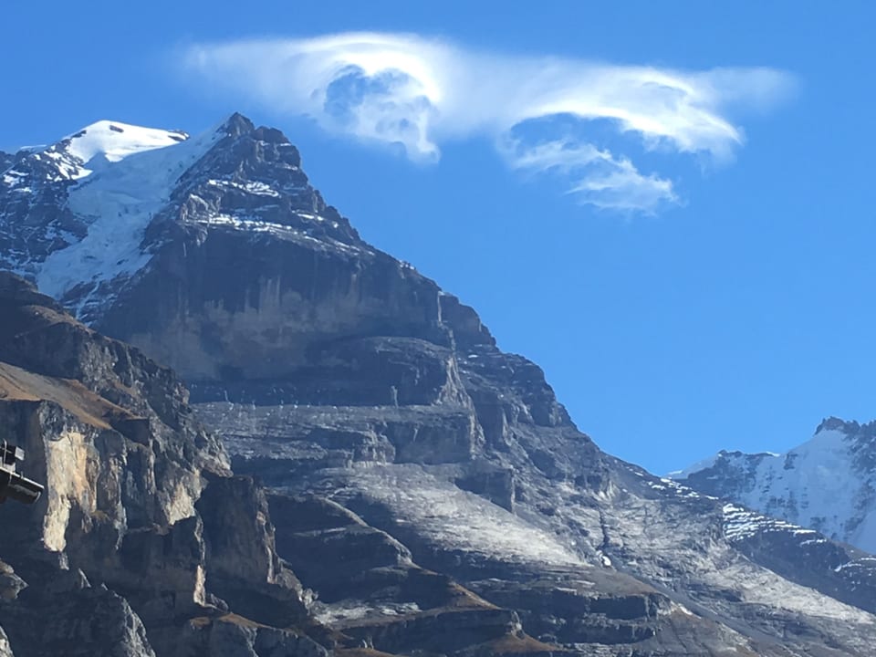 Wolken sehen aus wie Monster über dem Jungfraujoch. Sonst blauer Himmel.