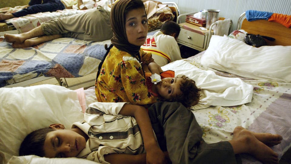 Irakische Mutter sitzt neben ihrem verletzten Kind auf einem Spitalbett