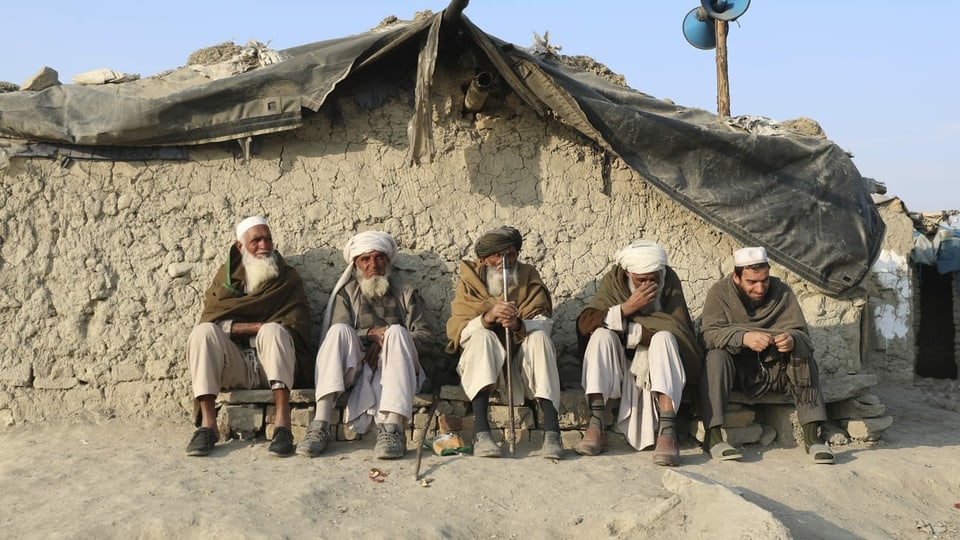 Afghanische Männer vor einer Lehmhütte