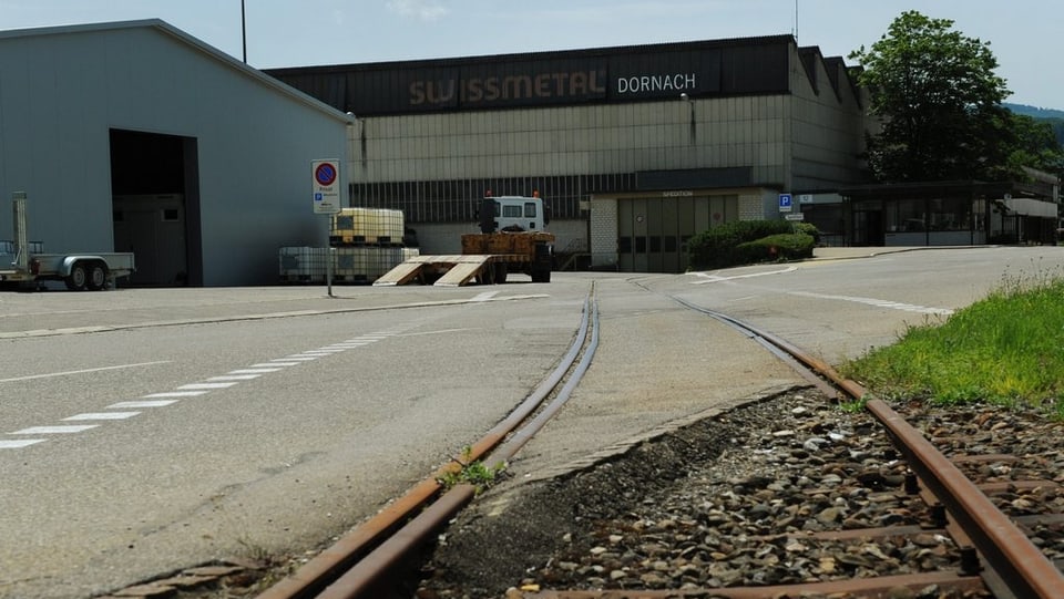 Blick auf zwei Fabrikgebäude der Swissmetal, im Vordergrund eine Strasse und ein Güterbahn-Gleis.