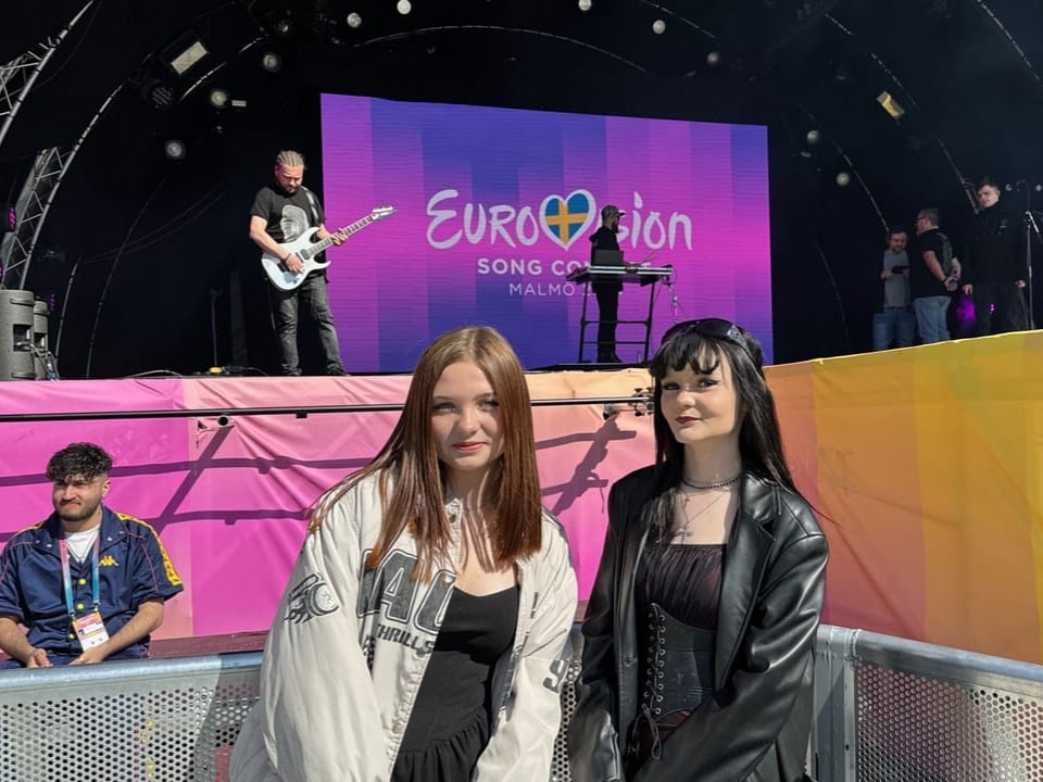 Zwei Frauen stehen vor einer Bühne mit dem Eurovision Song Contest Logo in Malmö.