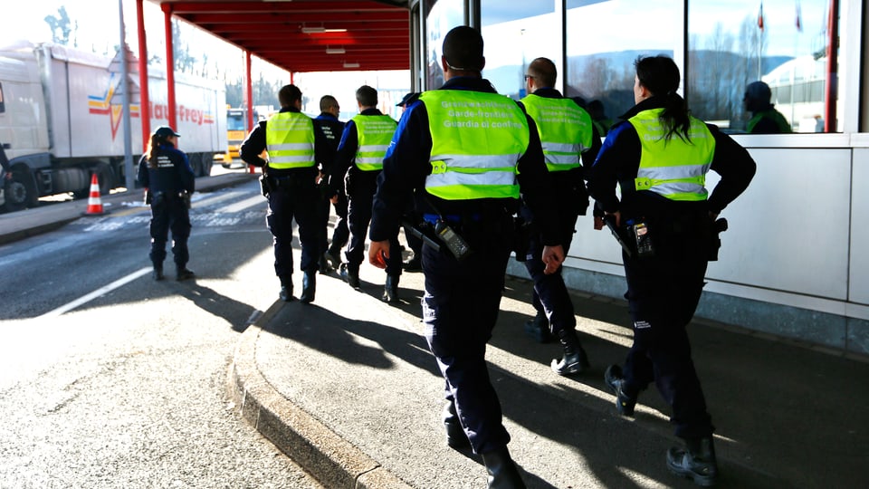 Polizeibeamte in Genf, von hinten, wie sie aus dem Bild marschieren.