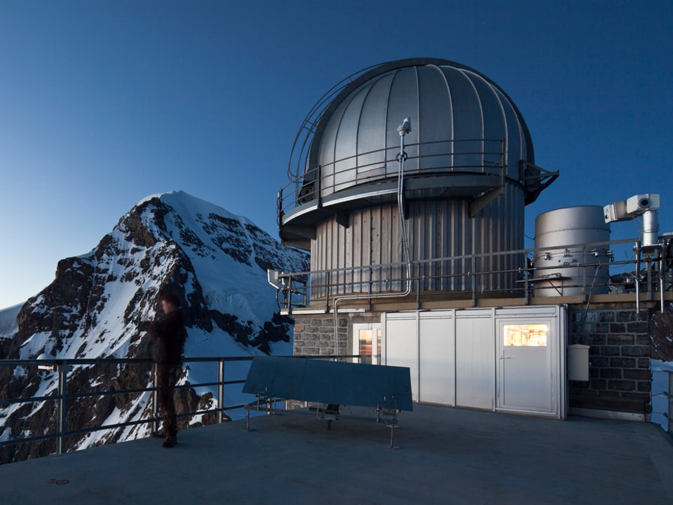 Ein Wissenschaftler steht vor der Forschungsstation am Jungfraujoch und macht ein Foto vom Nebel über dem Lauterbrunnental.