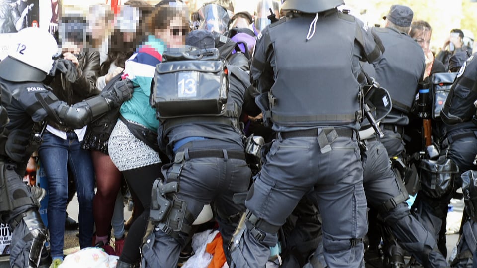 Polizeibeamte stellen sich gegen Demonstrantinnen.