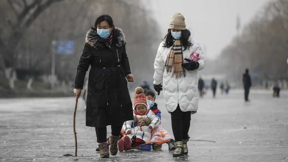 Zwei Frauen ziehen Kinder auf Schlitten in Schanghai