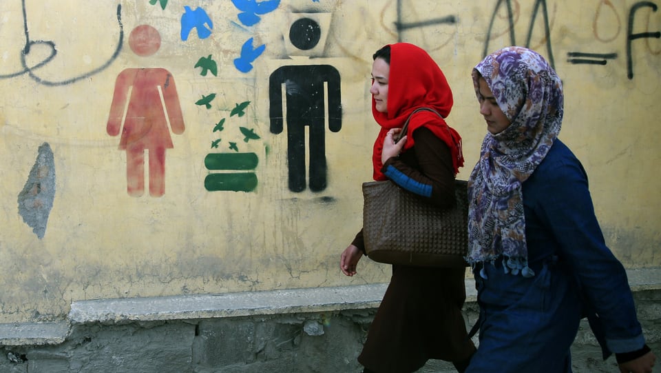 Zwei Frauen spazieren an Graffiti für Gleichberechtigung von Mann und Frau vorbei