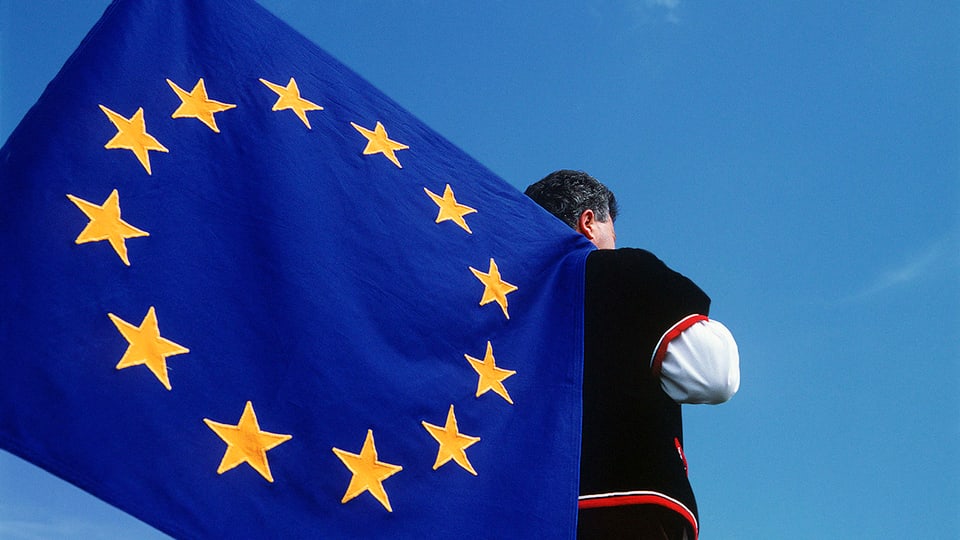 Symbolbild: Ein Fahnenschwinger in Sennentracht hat eine EU-Fahne auf der Schulter.