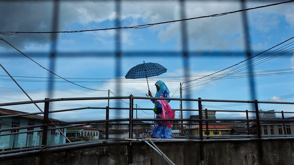 Frau mit Kopftuch und Regenschirm