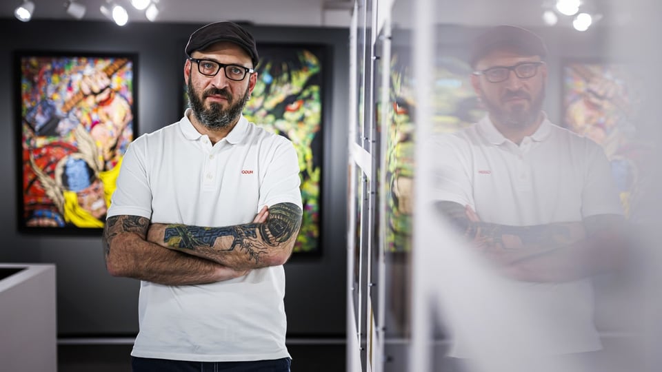 Breaking Boundaries Maison d'Ailleurs Hosts First Tattoo Convention in a Swiss Museum 5 Ein Mittvierziger mit Brille und Backenbart steht in einem Ausstellungsraum und verschränkt die Arme vor seiner Brust.
