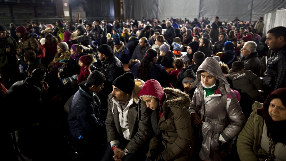 Gegen Hundert irakische Flüchtlinge warten in einer Halle auf einen Zug.