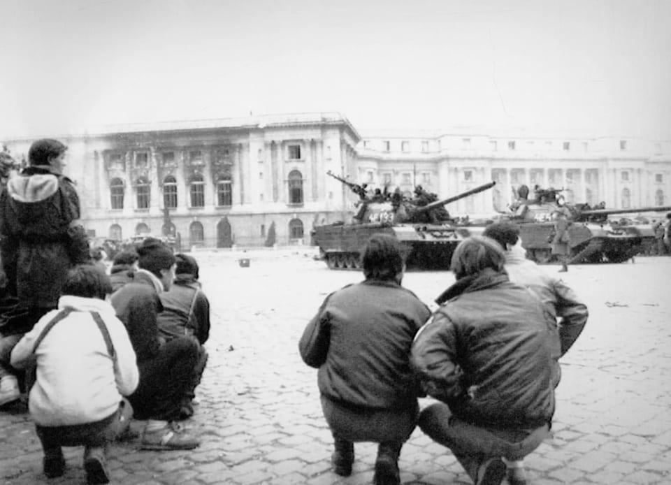 Menschen stehen vor dem Parlamentspalast in Bukarest, wo Panzer parkiert stehen