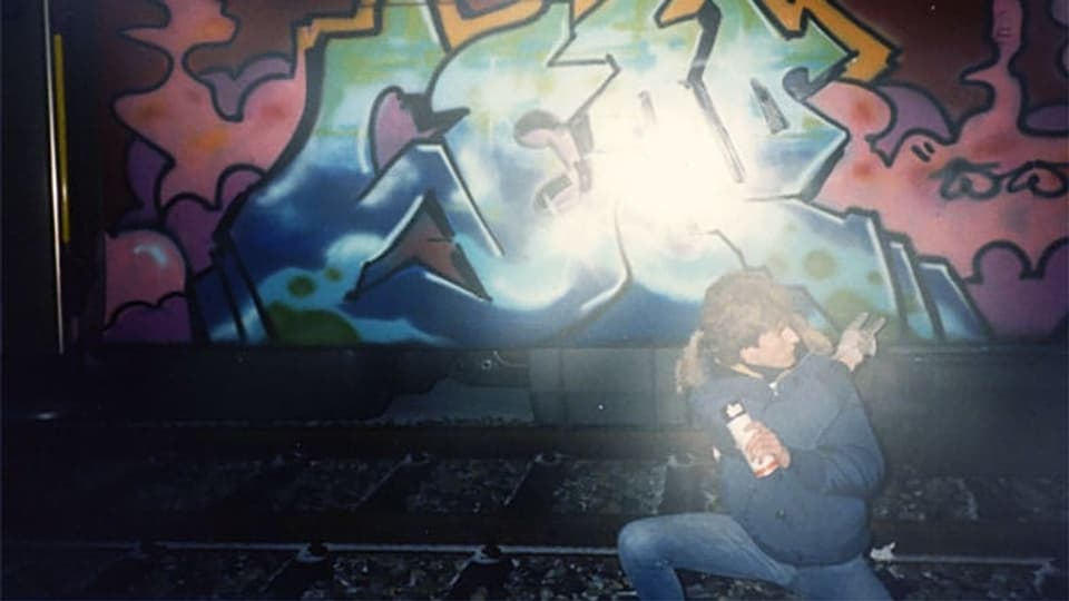 Ein Junge steht vor einem mit Graffiti besprayten Zug.