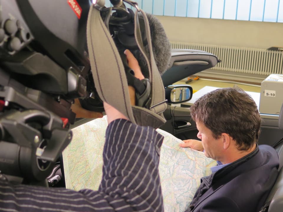 Kandidat Philippe Müller (FDP) sitzt im Cabriolet und studiert eine Landkarte. Im Vordergrund eine Kamerafrau.