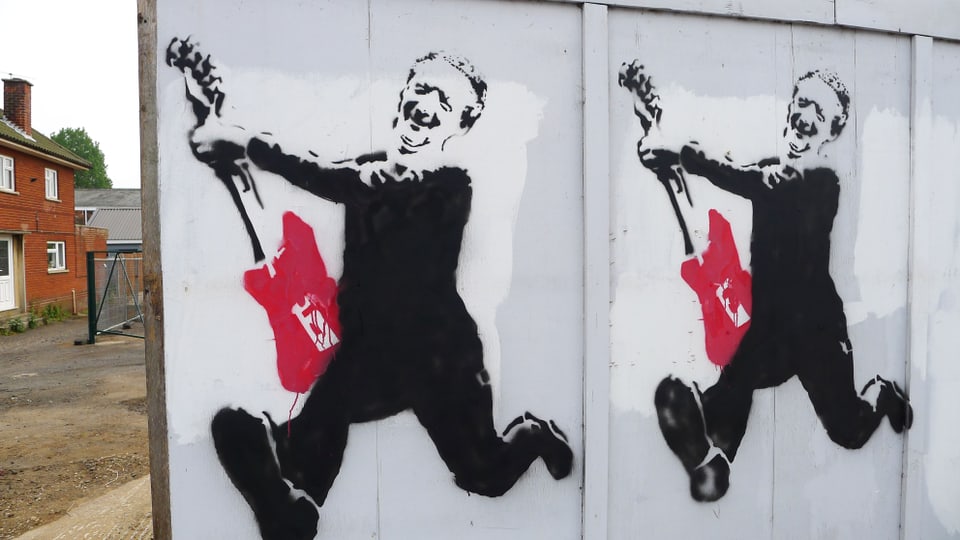 Ein Graffiti-Aufdruck an einer Holzwand in Aldeburgh, der Benjamin Britten mit roter elektrischer Gitarre zeigt.