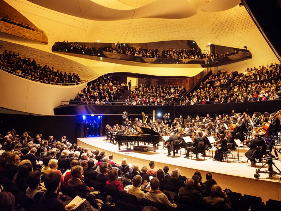 Konzertsaal in Gelbtönen mit wabenförmigen Rängen.