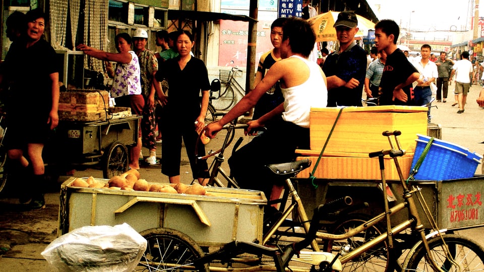 Strassenszene, Mann auf Fahrrad an Lebensmittelgeschäft, einige Frauen um ihn herum