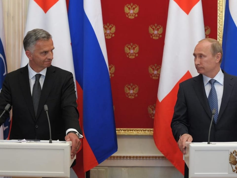 Burkhalter und Putin stehen beide hinter dem Rednerpult und schauen sich grimmig an. 