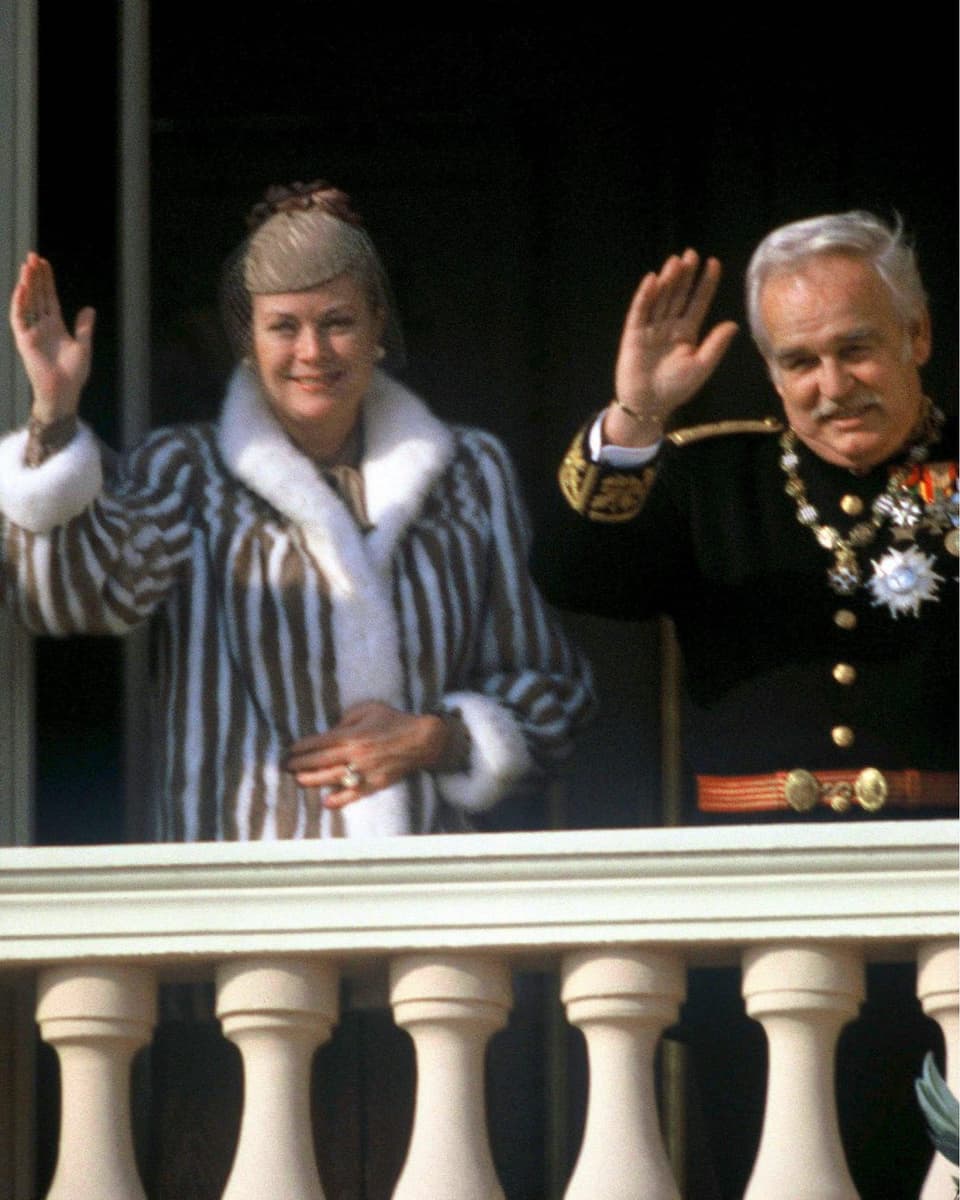 Fürstin Grace und Fürst Albert winken vom Balkon des Palastes. 