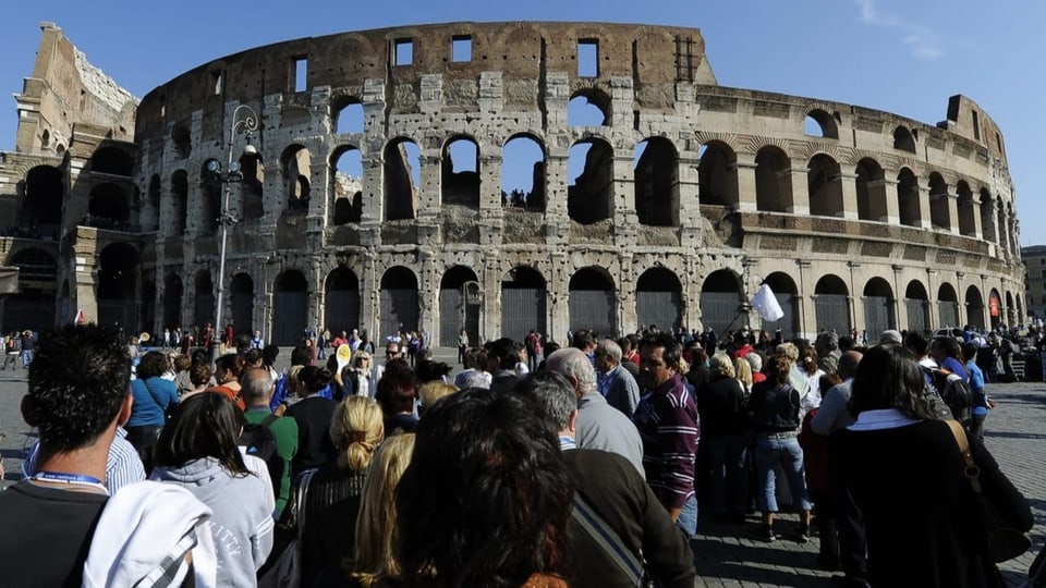 Touristen und Touristinnen stehen vor dem Kolosseum in Rom
