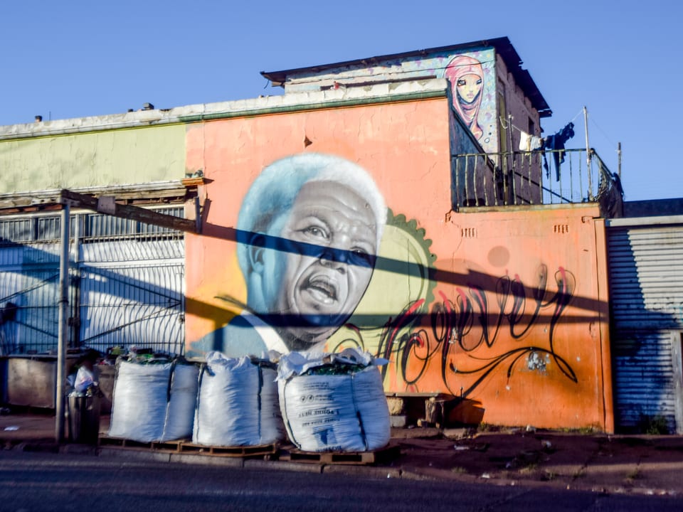 Grafitto, das einen älteren Nelson Mandela zeigt, auf der Rückseite eines Hauses.