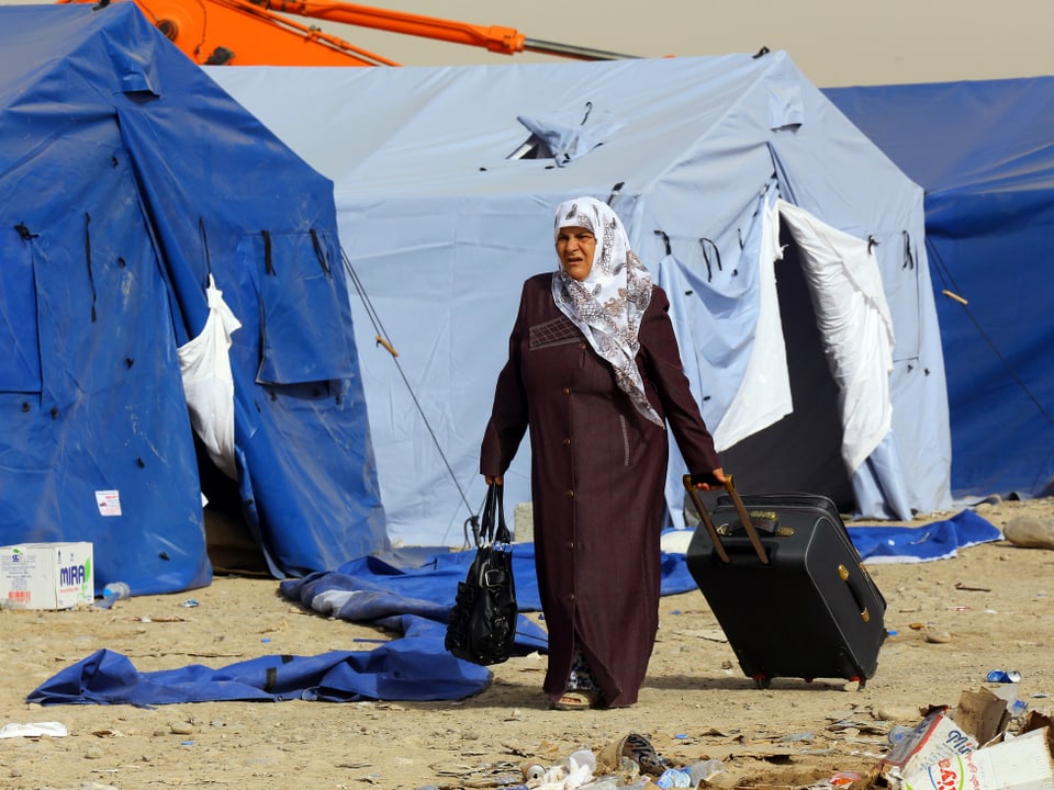 Frau zieht Koffer im Flüchtlingscamp
