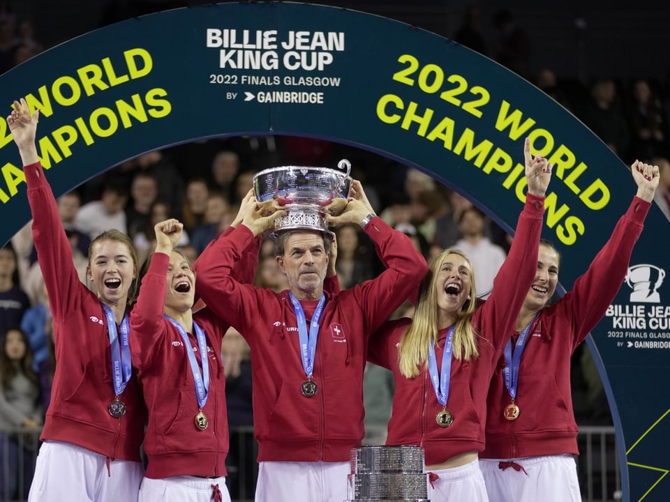 Tennis players and coach celebrate winning the world championship trophy.