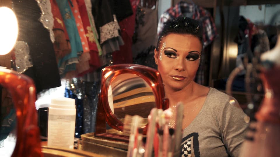 Eine Frau sitzt vor dem Spiegel und schminkt sich.