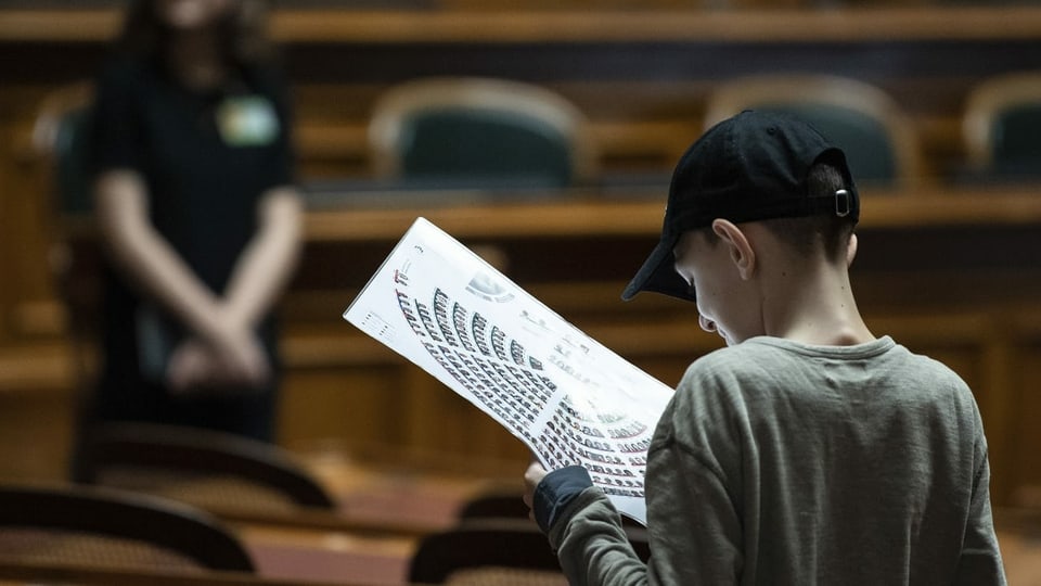Ein Junge studiert im Bundeshaus den Sitzplan des Nationalrats.