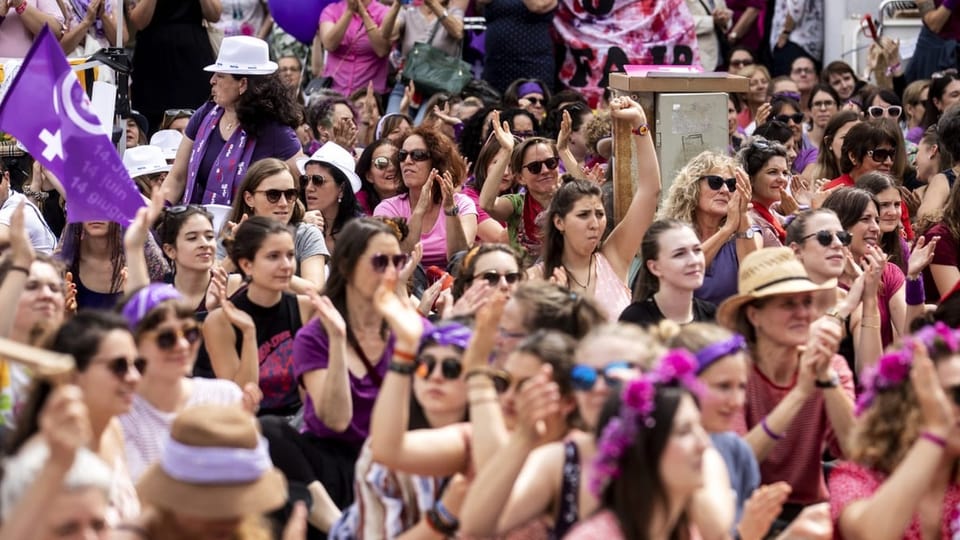 Demonstration mit zahlreichen Frauen in violetten Kleidern.
