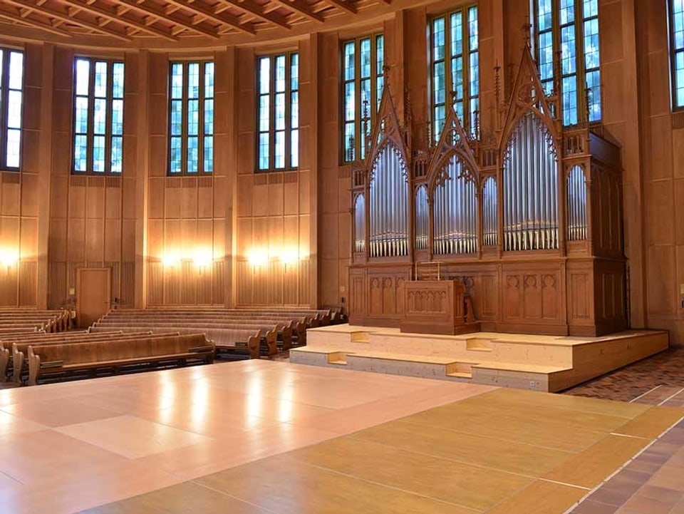 Auf der rechten Seite die grosse Orgel mit den vielen silbernen Pfeifen, links die Holzbänke der Kirche.