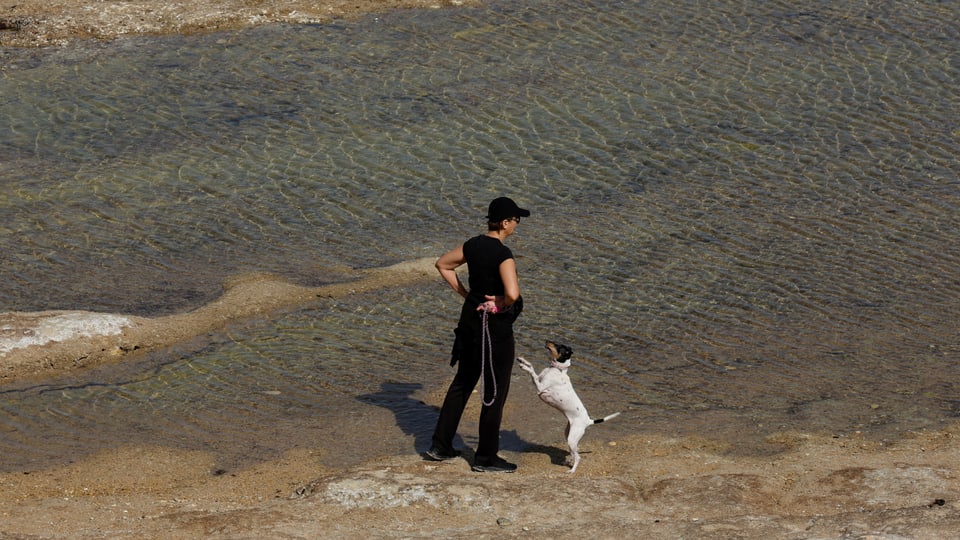 Eine Frau geht mit ihrem Hund entlang der maltesischen Küste.