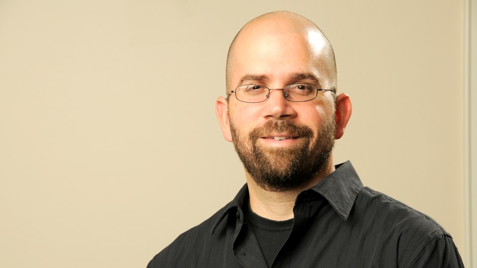 Porträt von Anthony Graesch mit Brille, Glatze und schwarzem Hemd.