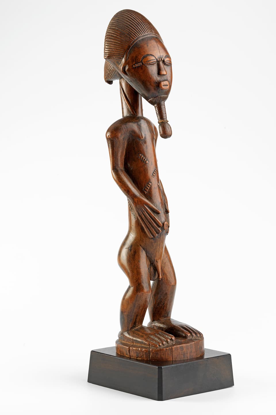 Eine männliche Figur aus Holz, die auf einem Sockel steht.