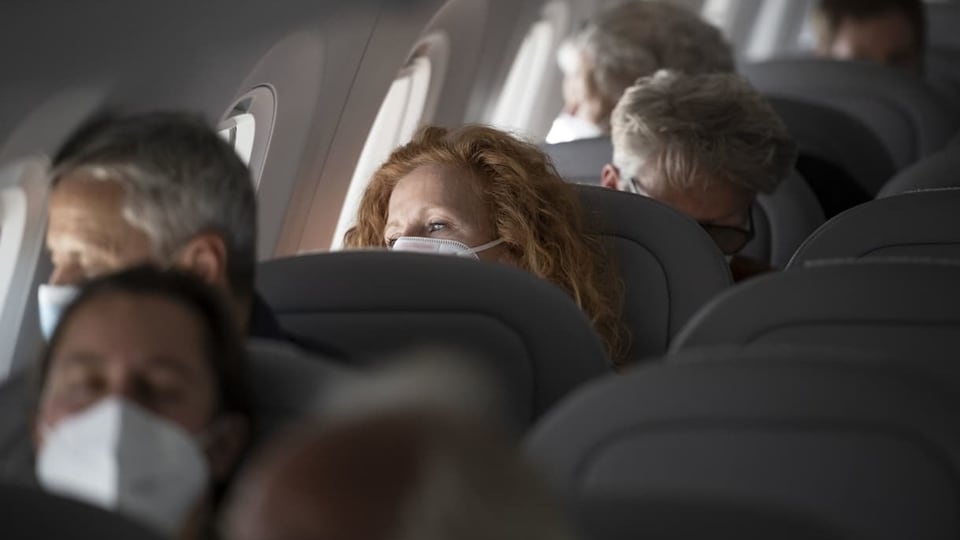 Menschen in einem Flugzeug tragen eine Maske.