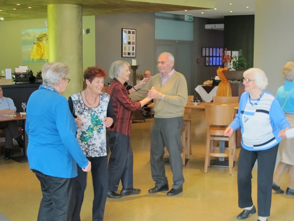 Ältere Damen und Herren tanzen in einem Raum.
