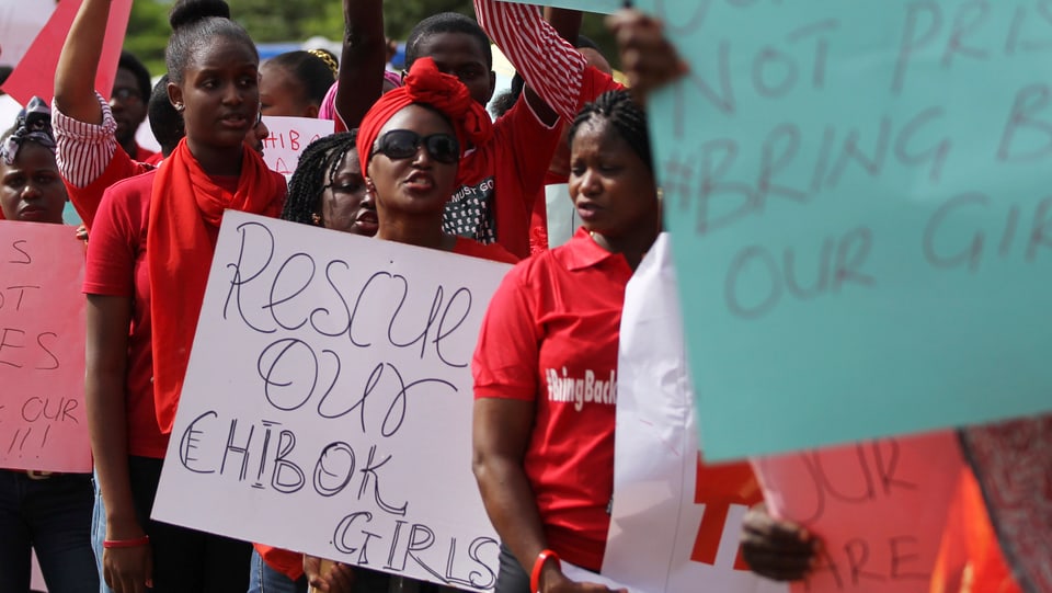 Demoteilnehmer in Abuja mit roten T-Shirts und Schildern, auf denen steht, rettet unsere Chibok-Mädchen.