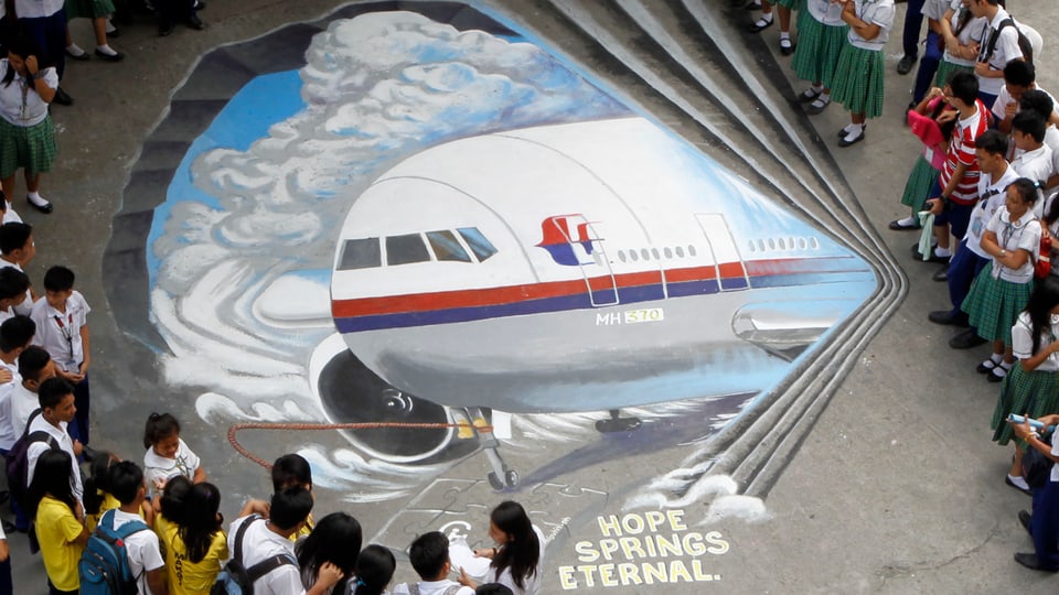 Kinder stehen um ein gemaltes Flugzeug.