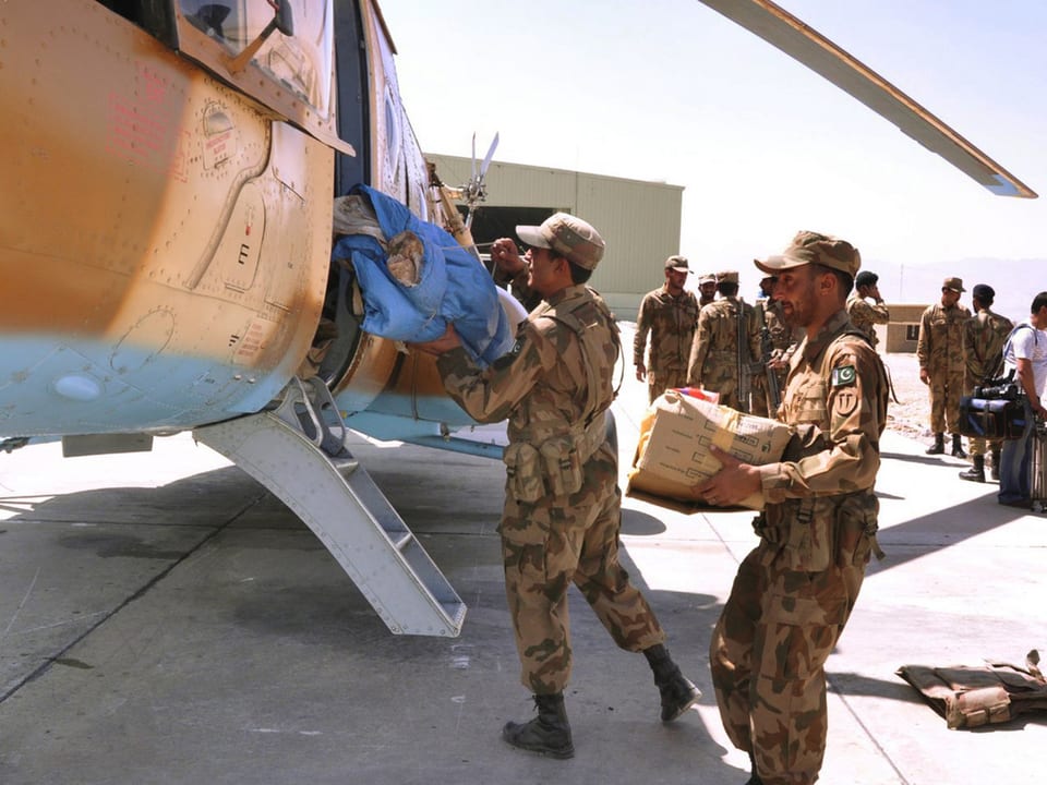 Soldaten laden verpackte Nahrung und Hilfsmittel in einen Helikopter. 