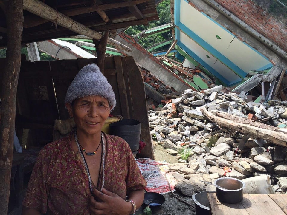 Eine Frau vor den Trümmern ihres Hauses