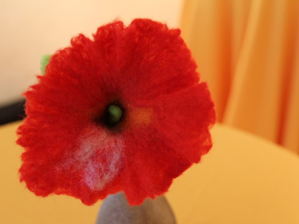 Eine rote Filzblume.