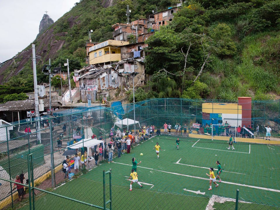 Ein Fussballfeld, auf dem Frauen spielen mitten in einer Favela.