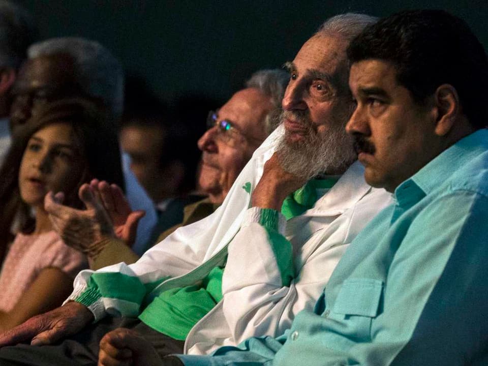 Castro, sein Bruder und andere Zuschauer sitzen in Reihen